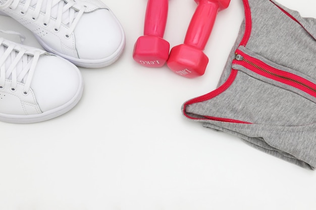 A pair of pink dumbbells, a pair of pink dumbbells, and a pair of white sneakers.