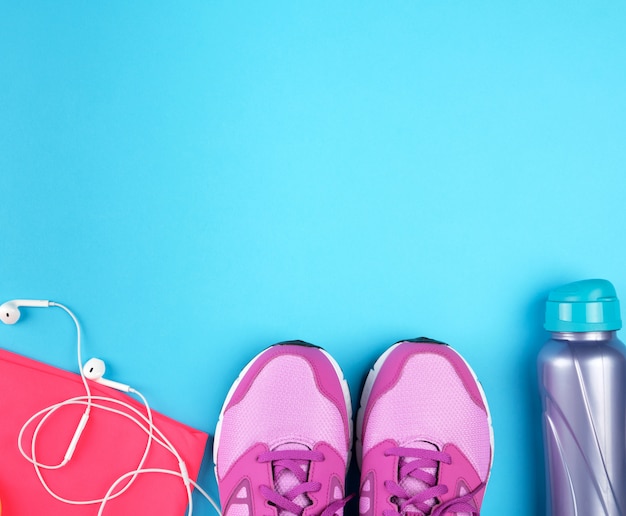 Pair of pink sneakers with laces on blue, top view, copy space