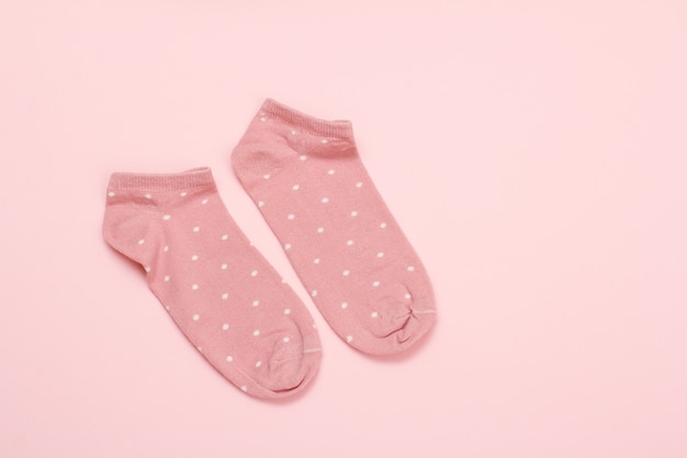 Pair of pink women socks on a pink background, Top view.