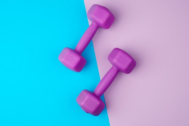 Photo pair of purple plastic dumbbells on a blue-violet background