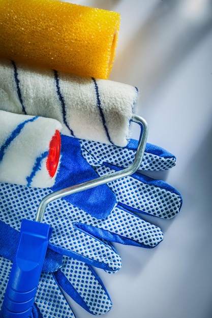 Pair of safety gloves paint rollers on white background