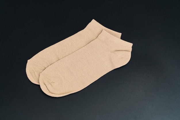 A pair of short beige socks on a black background. accessories for men and women. clothing store.