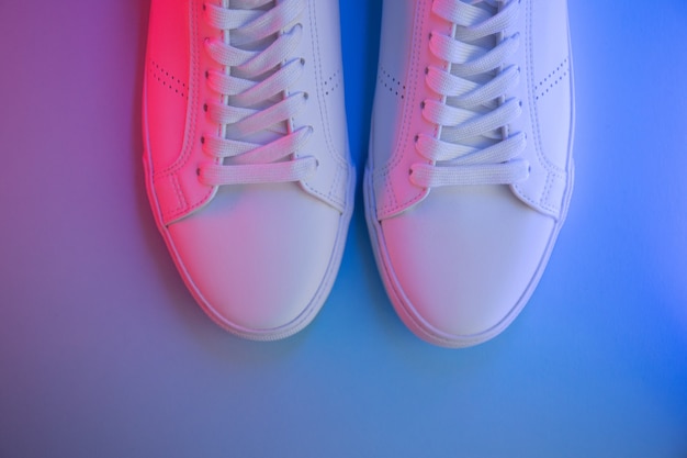 Pair of sneakers on color background, top view.