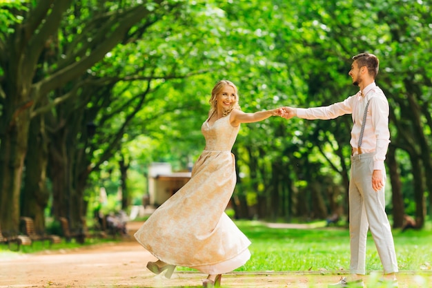 A pair of stylish clothes dancing in a park on the background of trees