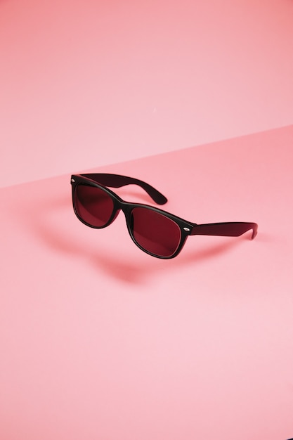 Pair of sunglasses over a pastel pink background minimal concept