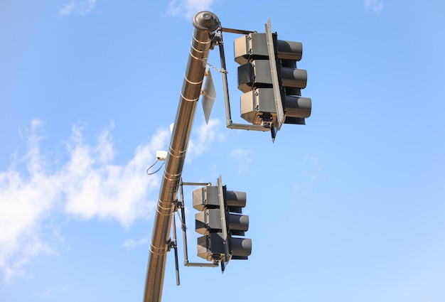 A pair of traffic lights with a blue sky behind them.