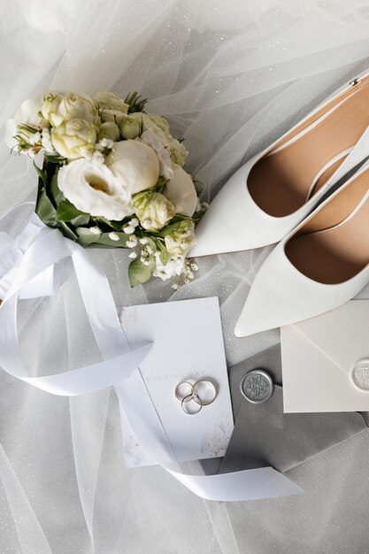 Photo a pair of wedding shoes a bouquet of flowers a wedding invitation and a pair of wedding rings