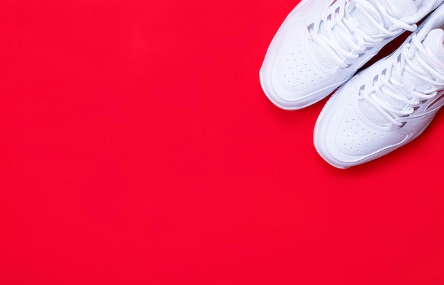 A pair of white sneakers on a red background The concept of a healthy lifestyle Copy space Banner