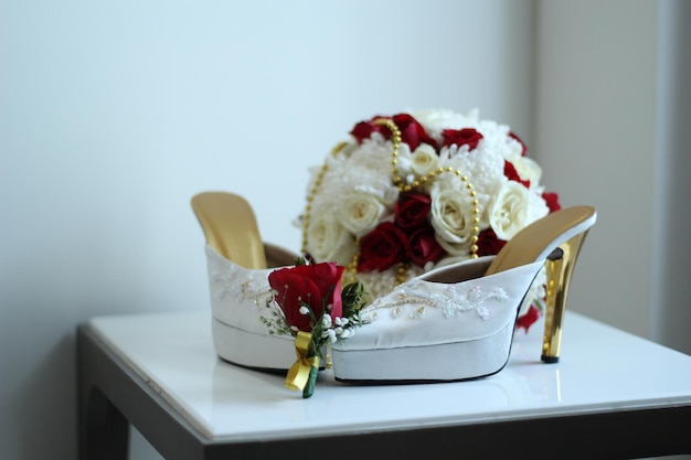 A pair of white women39s high heels and a beautiful rose flower bucket