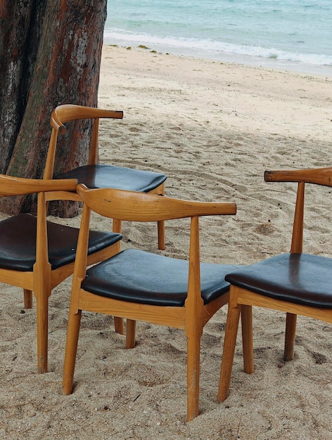 Photo a pair of wooden chairs sit on the beach in mexico.