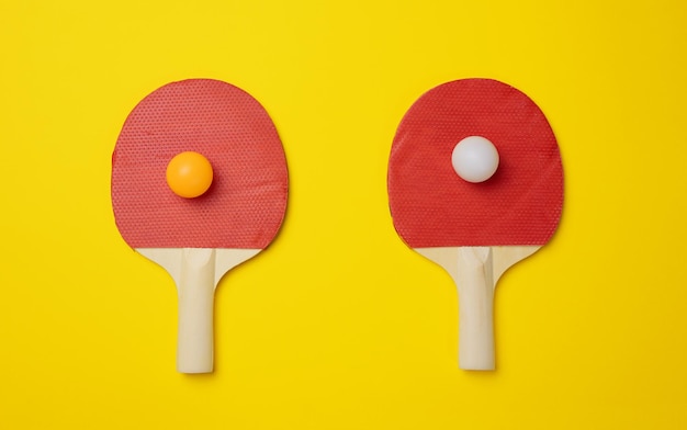 Pair of wooden tennis rackets for ping pong on a yellow background