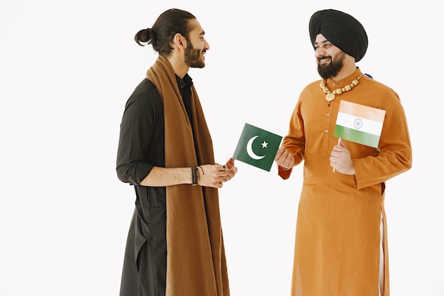 Pakistani man and Indian men in traditional clothes. The friends are talking at white background, isolated. Agremment between countries.