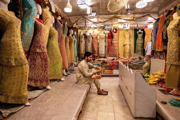 Pakistani man selling colorful fabric and dresses on the Qissa Khwani Bazaar in Peshawar Pakistan