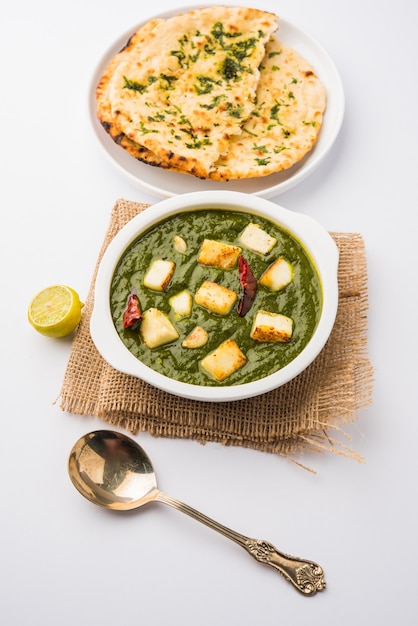 Palak Paneer Curry made up of spinach and cottage cheese, Popular Indian healthy Lunch or Dinner food menu, served in a Karahi with Roti Or Chapati over moody background. selective focus