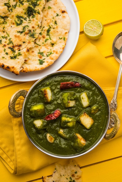 Palak Paneer Curry made up of spinach and cottage cheese, Popular Indian healthy Lunch or Dinner food menu, served in a Karahi with Roti Or Chapati over moody background. selective focus