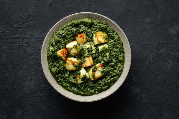 Palak paneer indian traditional food with cheese and spinach on black background view from above