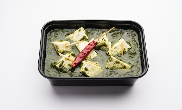 Palak Paneer with rice and chapati packed in a plastic container ready for home delivery