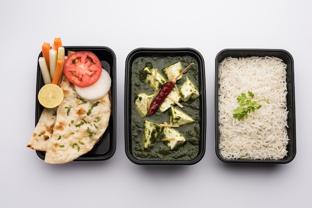 Palak Paneer with rice and chapati packed in a plastic container ready for home delivery