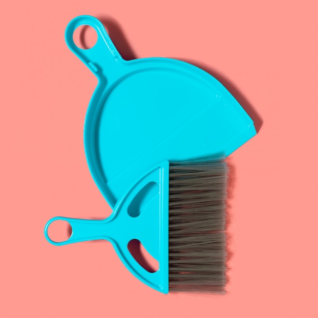 A pale blue dustpan and brush lying on living coral background