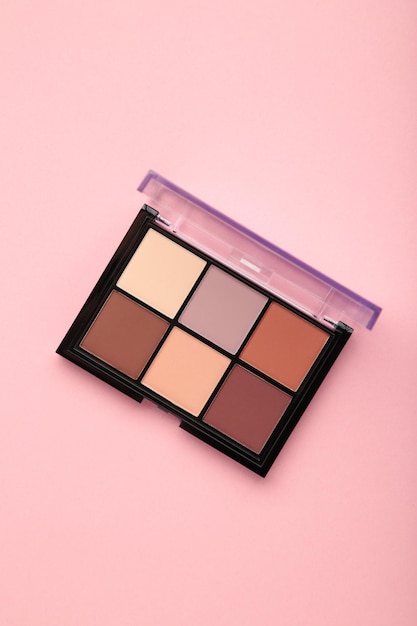 Palette of basic eyeshadows on pink background Makeup concept Vertical photo