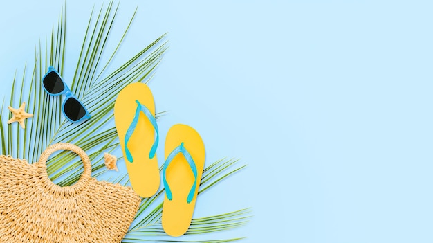 Palm leaves beach bag flip flops glasses and seashells