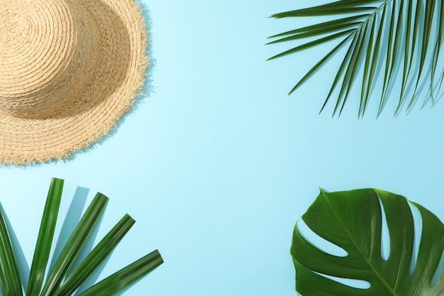 Palm leaves and straw hat on blue table