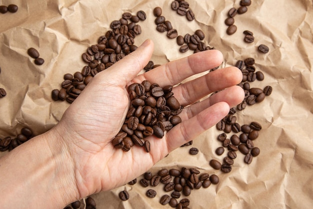 Palm scoops up coffee beans scattered on kraft paper