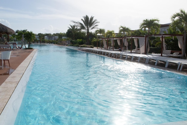 Palm tree with umbrella and chair in the luxury hotel pool resort at summer times