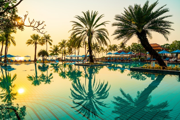 palm tree with umbrella chair pool in luxury hotel resort at sunrise times