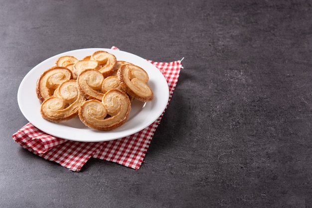 Palmier puff pastry in plate on black slate background