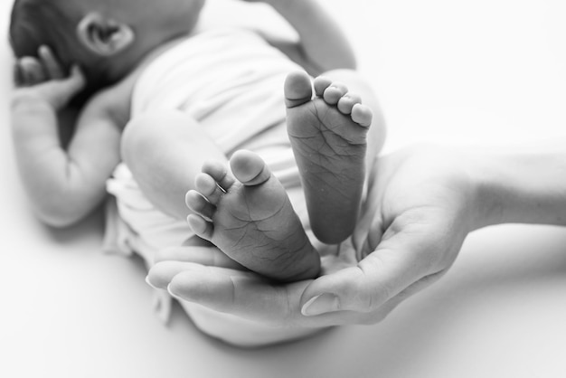 Photo the palms of the father the mother are holding the foot of the newborn baby feet of the newborn on the palms of the parents studio macro black and white photo of a childs toes heels and feet