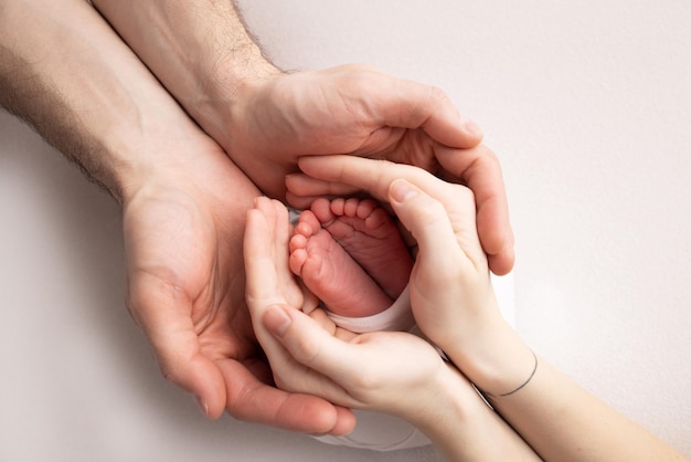 The palms of the father the mother are holding the foot of the newborn baby Feet of the newborn on the palms of the parents Studio photography of a child39s toes heels and feet Concept