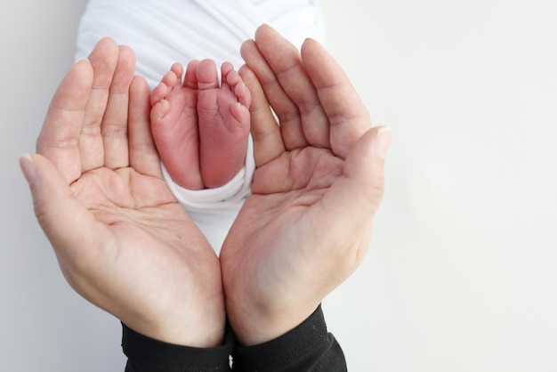 The palms of the father the mother are holding the foot of the newborn baby in a white blanket Feet of the newborn on the palms of the parents Studio photography of a child39s toes heels and feet