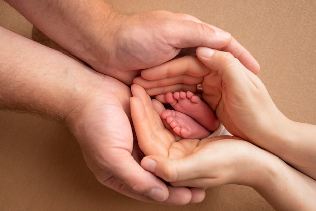 The palms of the parents A father and mother hold the feet of a newborn child The feet of a newborn in the hands of parents Photo of foot heels and toes