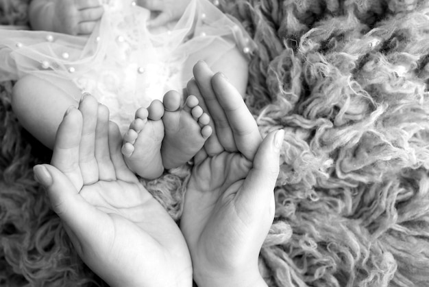 Photo the palms of the parents a father and mother hold the feet of a newborn child in a flakatty the feet of a newborn in the hands of parents black and white photo of foot heels and toes