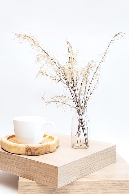 Pampas grass in glass vase on wooden table near white wall