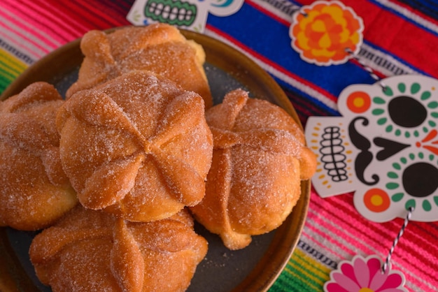 Pan de muerto with sugar skull figures on colorful serape Day of the Dead celebration