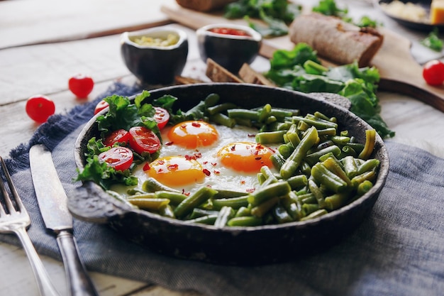 Pan of fresh fried eggs with tomatoes green beans bread spices and herbs