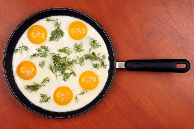 Photo the pan on the table with fried scrambled eggs with dill and sesame seeds