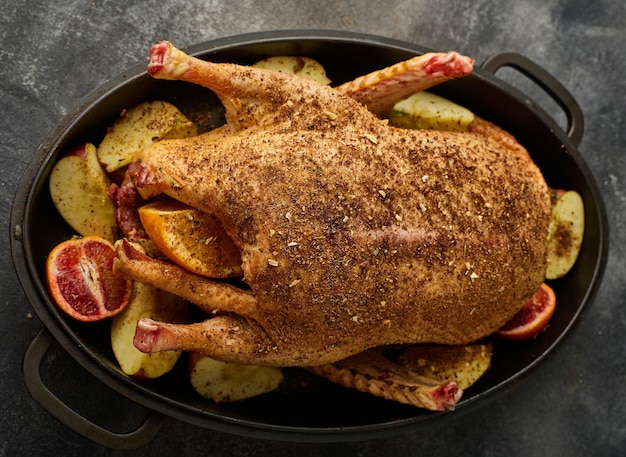 In a pan a whole duck prepared with spices in combination with apples and oranges for roasting