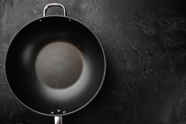 Pan with handle wok set with copy space for text or food with copy space for text or food top view flat lay on black dark stone table background