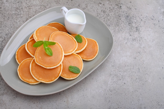 Pancake in a plate decorated with mint on a concrete table