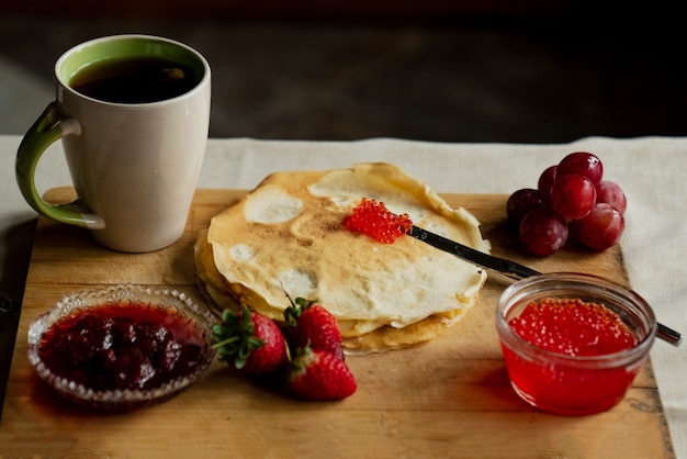 Pancake with red caviar for breakfast, a cup of tea