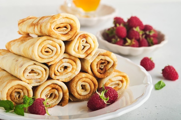 Pancakes Stack of crepes or thin pancakes with berries with raspberries and honey for breakfast Homemade breakfast Copy space Selective focus