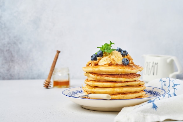 Pancakes with banana, walnut, honey and caramel for a breakfast. Selective focus.