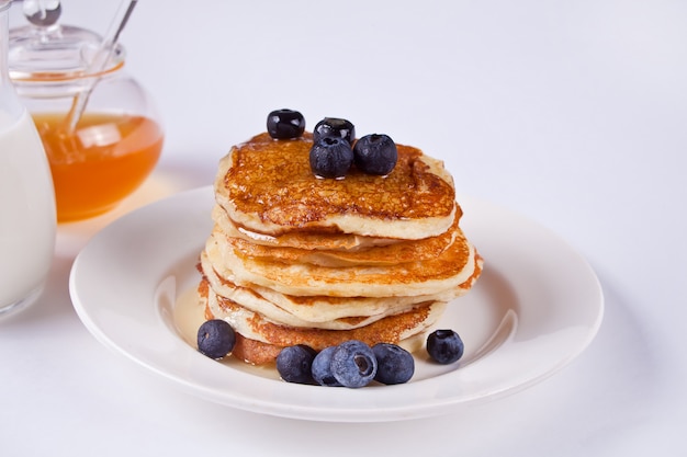 Pancakes with berries and honey on the white background