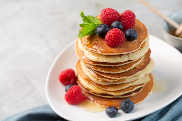 Pancakes with blueberries, raspberries, mint and honey for a breakfast