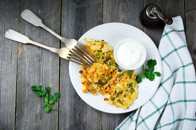 Pancakes with cabbage and spinach on a white ceramic plate on old wooden table. Rustic style. Selective focus.Top view. Place for text.