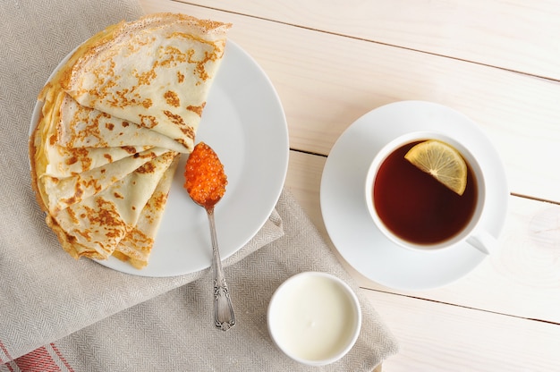 Pancakes with caviar and sour cream on a saucer