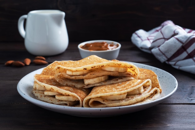 Pancakes with chocolate banana filling Wooden rustic table sweet delicious dessert